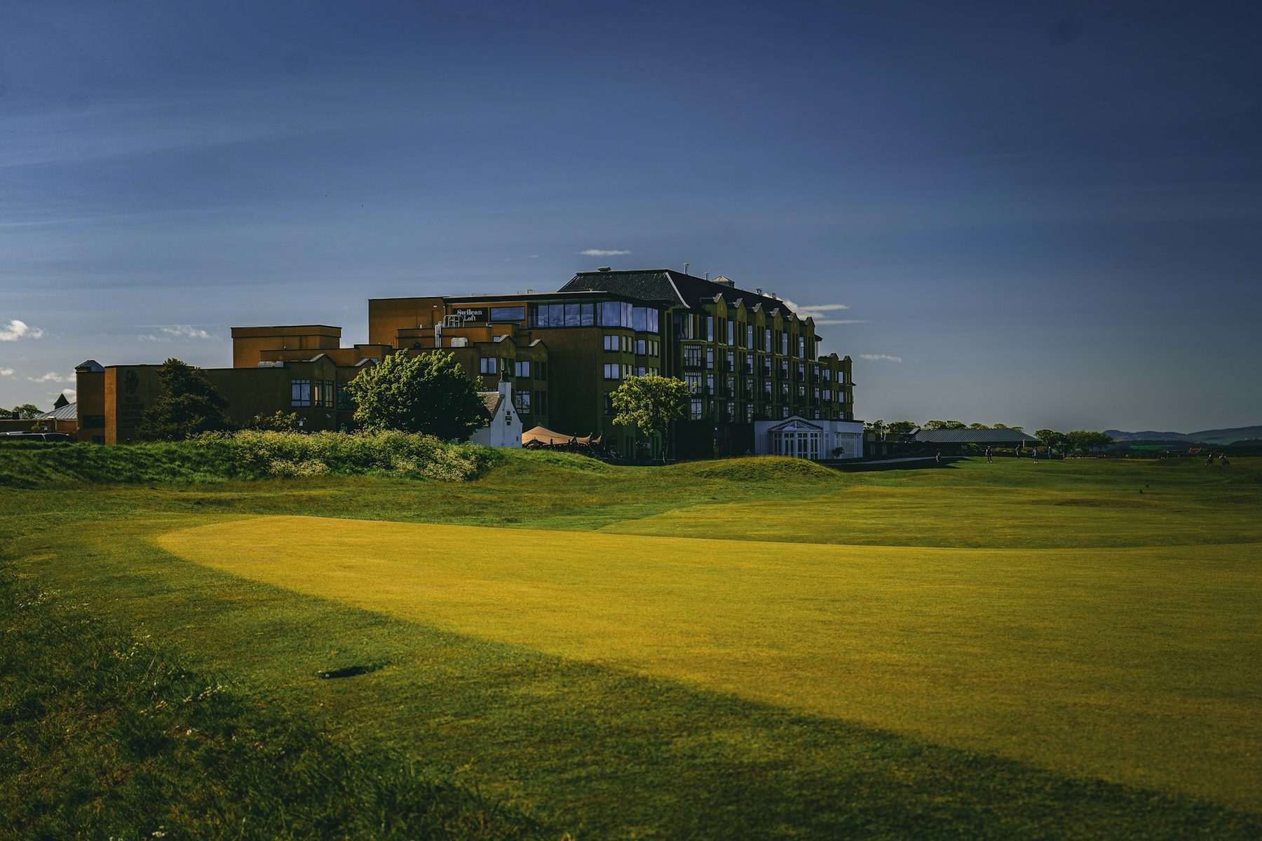 A clubhouse beyond the fairway in late light.