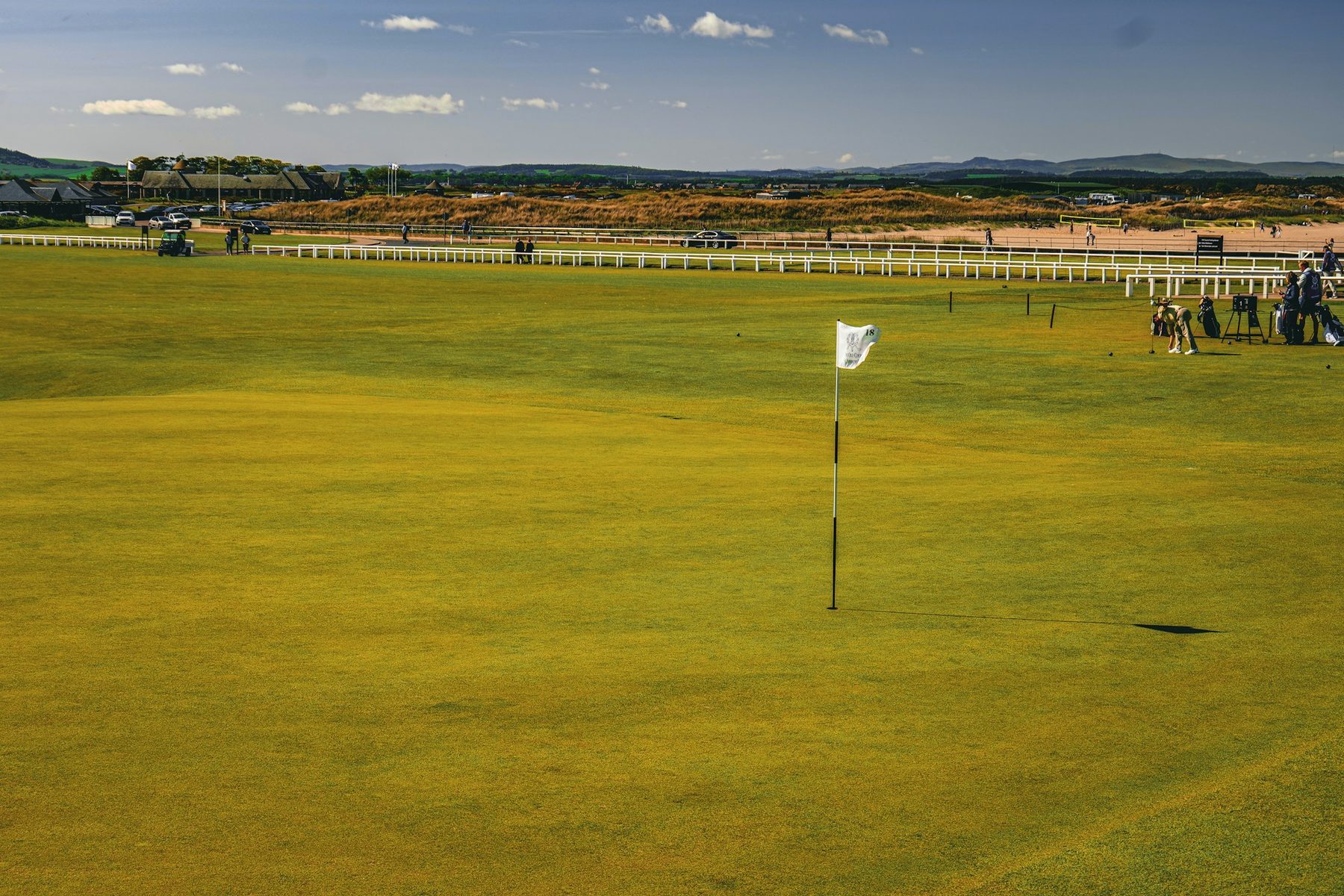 A white flag on a broad green, late in the day.