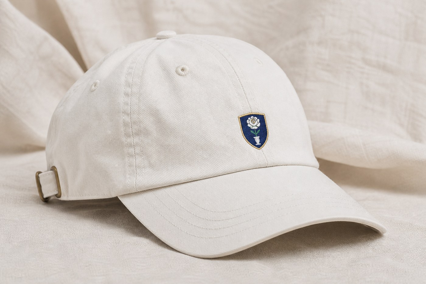 A white chino dad hat with a small Rosedale Cup seal.