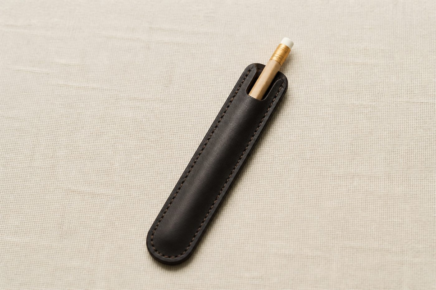 A dark leather pencil sleeve with a wooden scorecard pencil tucked inside.