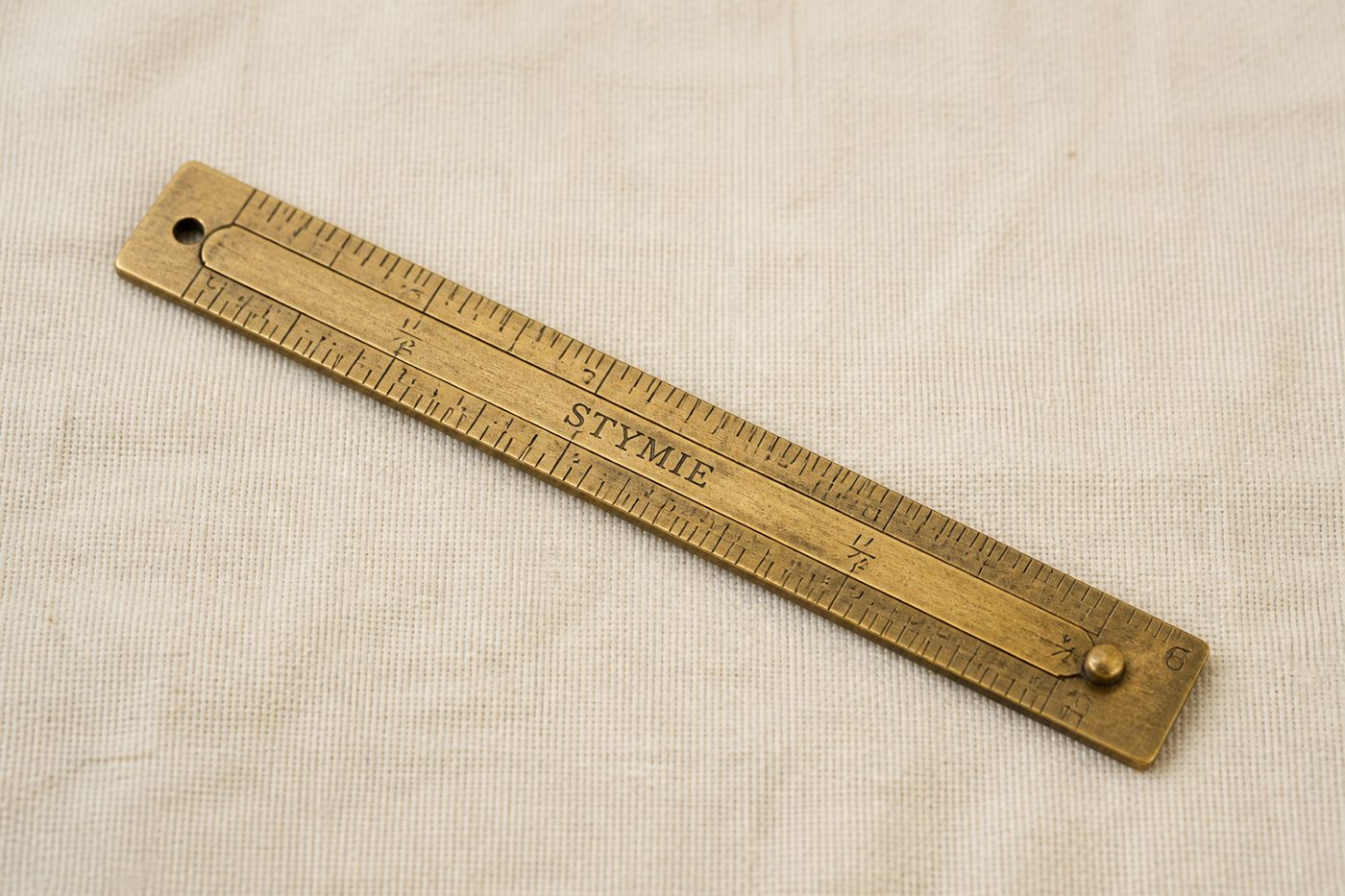 A six-inch brass stymie measure with a sliding gauge, engraved STYMIE.