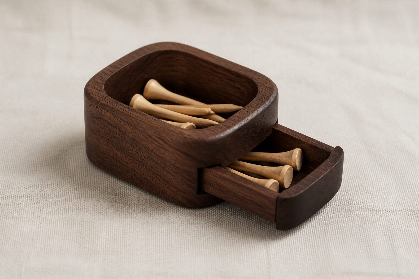 A dark wooden tee caddy with a top well and a small drawer, both filled with wooden tees.